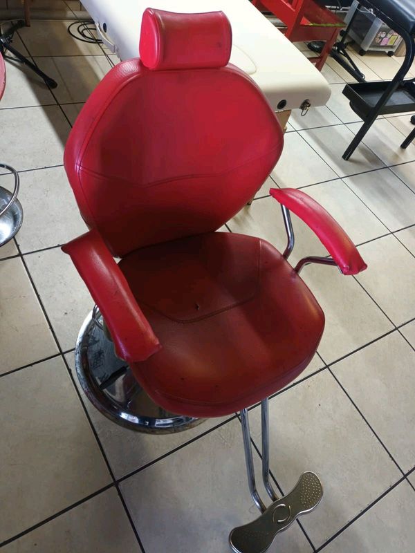 Old school adjustable red barber chair with hydraulic foot press and foot rest