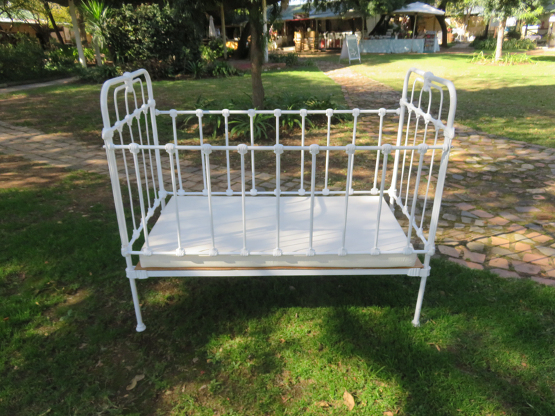 Antique white painted wrought iron baby cot with drop sides.