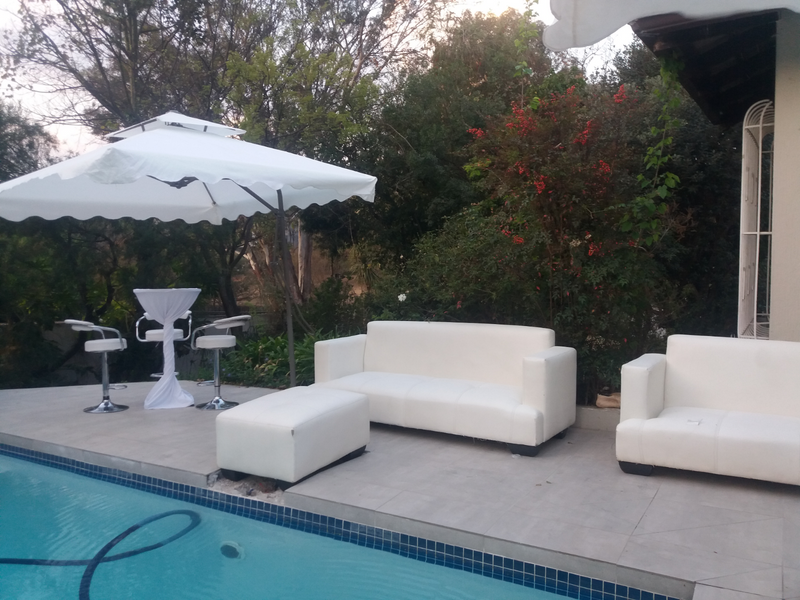 White couches set up by the pool with garden umbrellas
