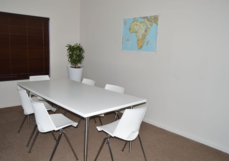 Meeting room solid wood table with 5 white 4-legged chrome chairs
