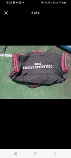 Pull along cricket kit bag with cricket items including set of DP pads and cricket bat