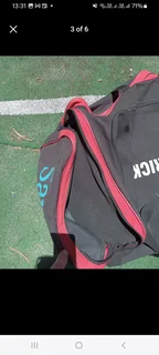 Pull along cricket kit bag with cricket items including set of DP pads and cricket bat