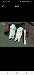 Pull along cricket kit bag with cricket items including set of DP pads and cricket bat