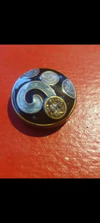 vintage glass button with a flower or scroll pattern and rhinestone accents.
