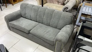 The Home Stores' Two Seater Grey Sleeper Couch With Gold Strip Studs On Armrest