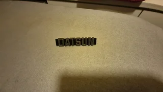Datsun name emblem chrome with black background.