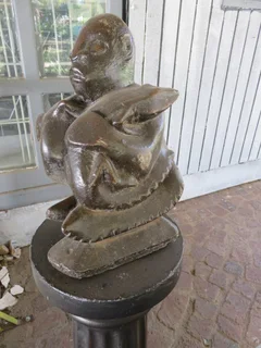 Concrete man seated with a mythical lizard type creature.