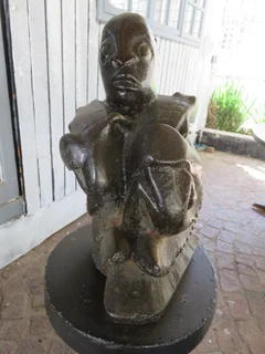 Concrete man seated with a mythical lizard type creature.