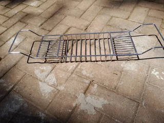 Stainless steel bath caddy fits across the bath to keep soap, cosmetics