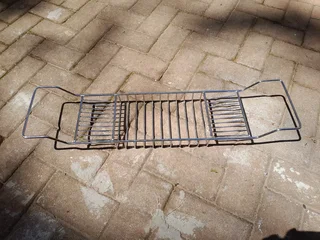 Stainless steel bath caddy fits across the bath to keep soap, cosmetics