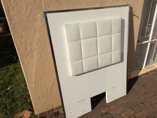 A white upholstered headboard for kids bed with a tufted, square-patterned design.