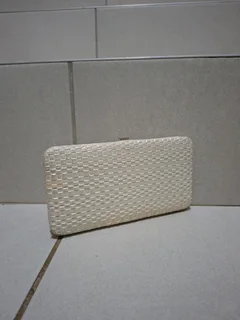 Woven clutch wallet with a metal frame.